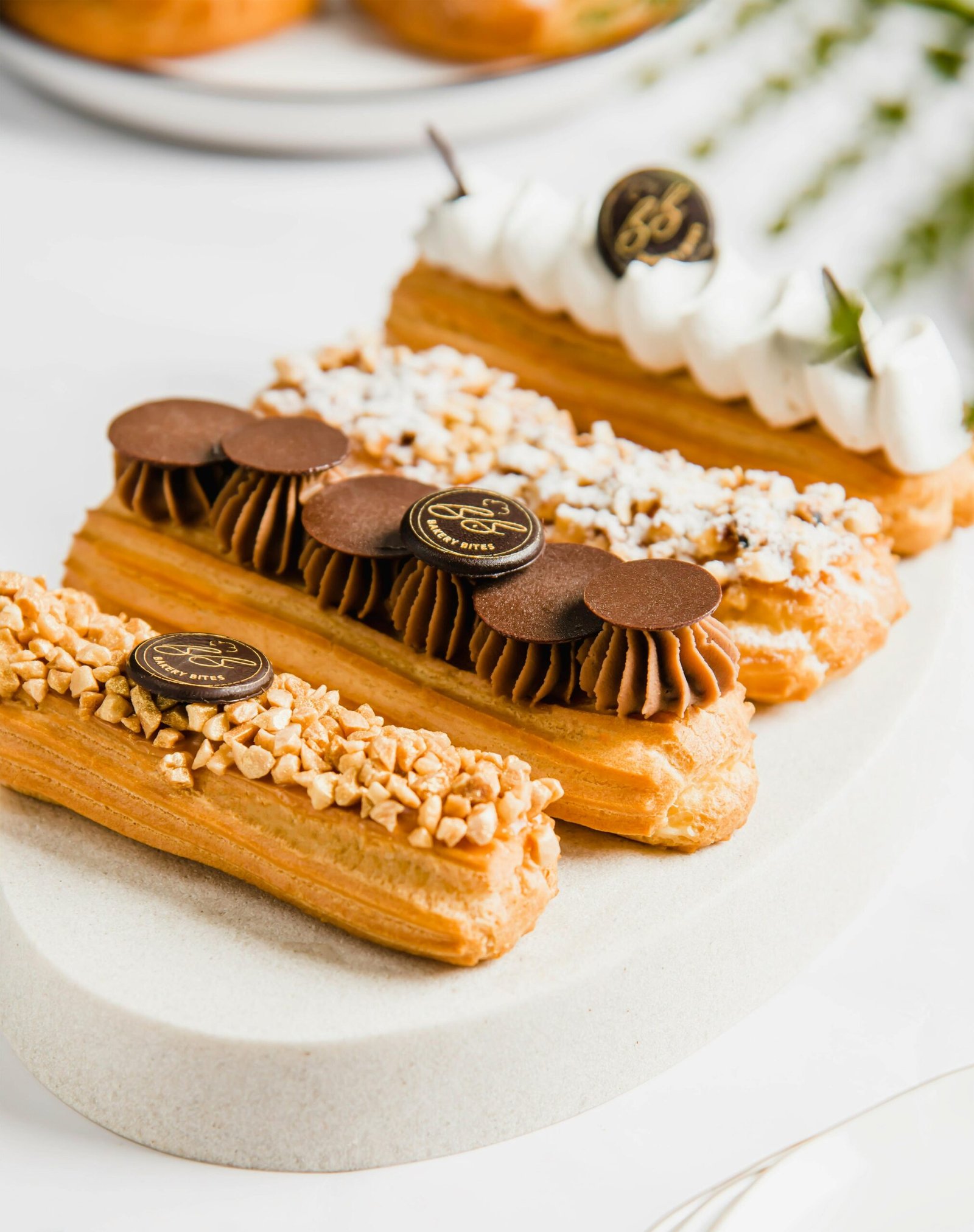 Close-up of delicious artisanal eclairs with assorted toppings on a white platter.